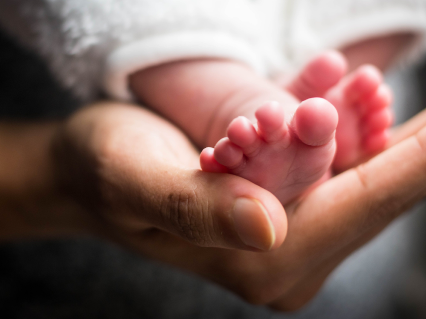 parent holding newborn baby's small feet