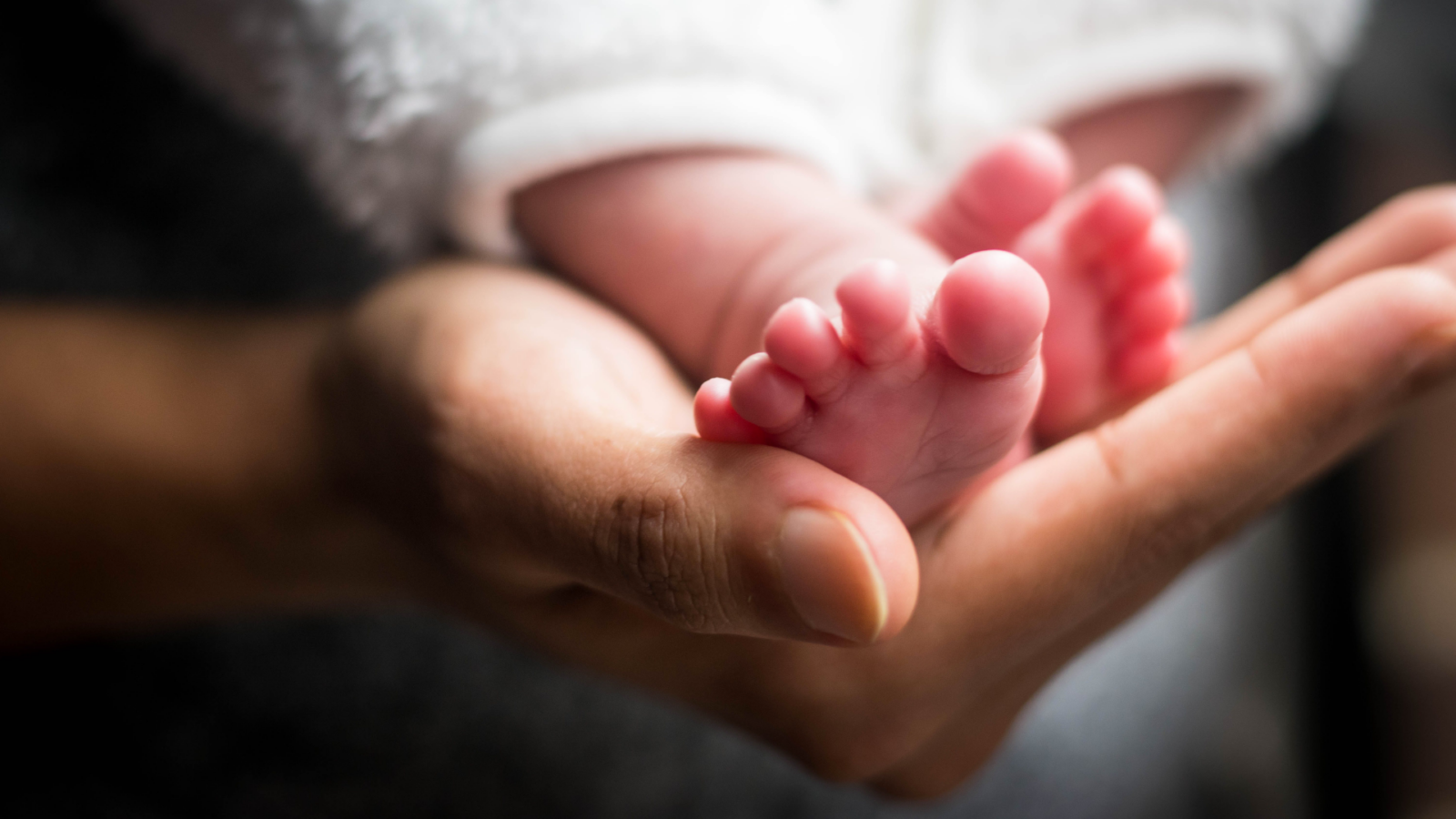 Woman holding newborn baby's small feet